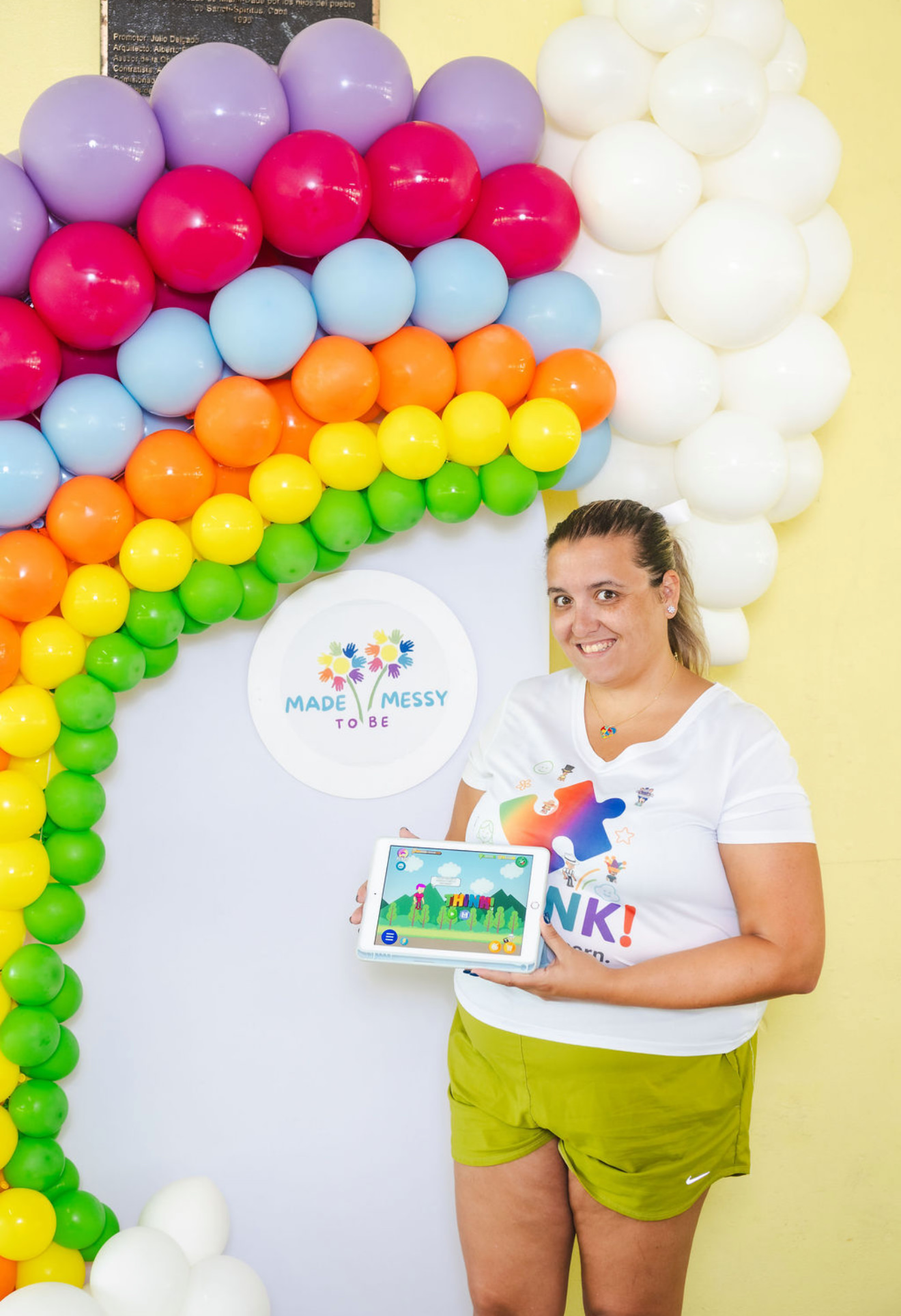 Made Messy to Be booth with rainbow balloon arch