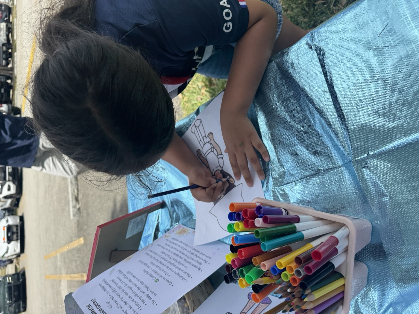 Focused and creative — a child draws at our outdoor station, lost in their imagi