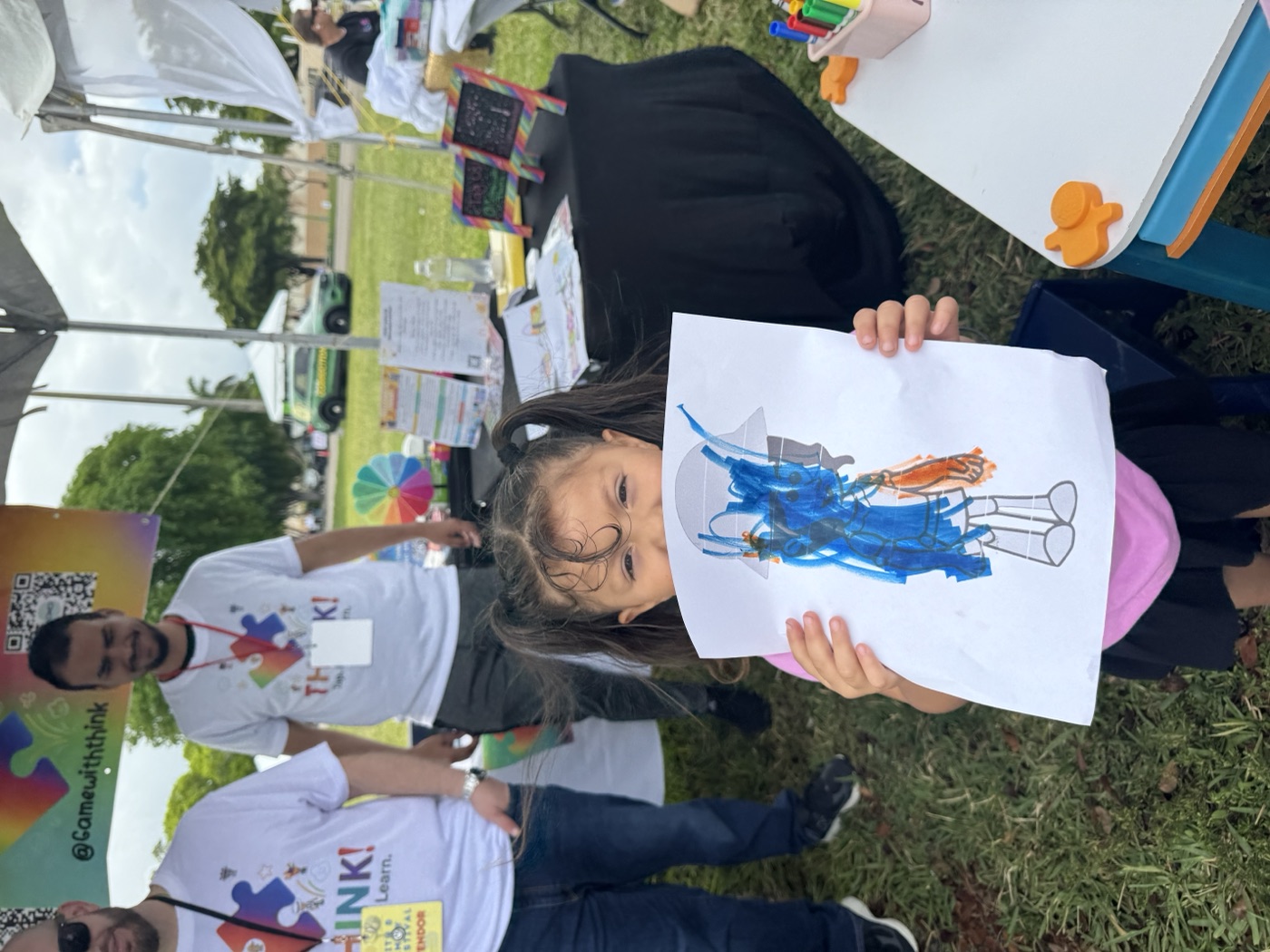 Blue is the color of the day! A child holds up their artwork with a big grin.